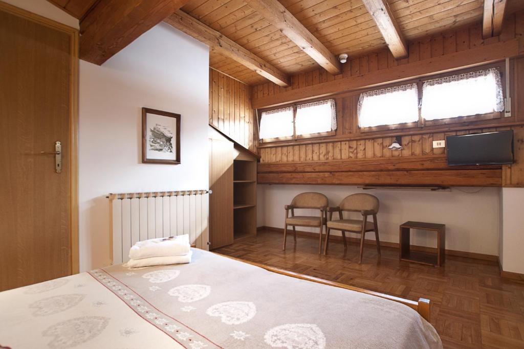 une chambre avec un lit, deux chaises et une télévision dans l'établissement Albergo Meublè Victoria, à Auronzo di Cadore