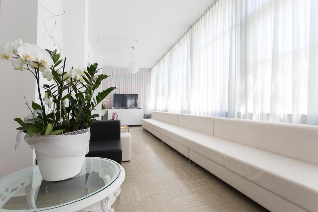 un salon avec un canapé et une table avec des fleurs dans l'établissement Hotel Bristol - Koolibry Hotels, à Cervia