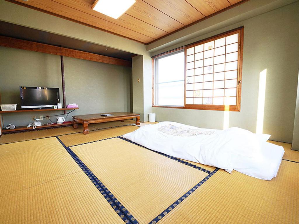 une chambre avec un lit et une télévision dans l'établissement business ryokan haniwa, à Saito