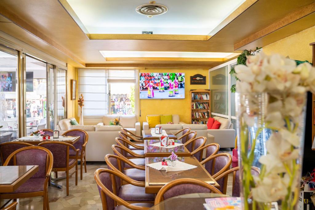 un restaurant avec des tables, des chaises et un canapé dans l'établissement Hotel Harry's, à Lido di Jesolo