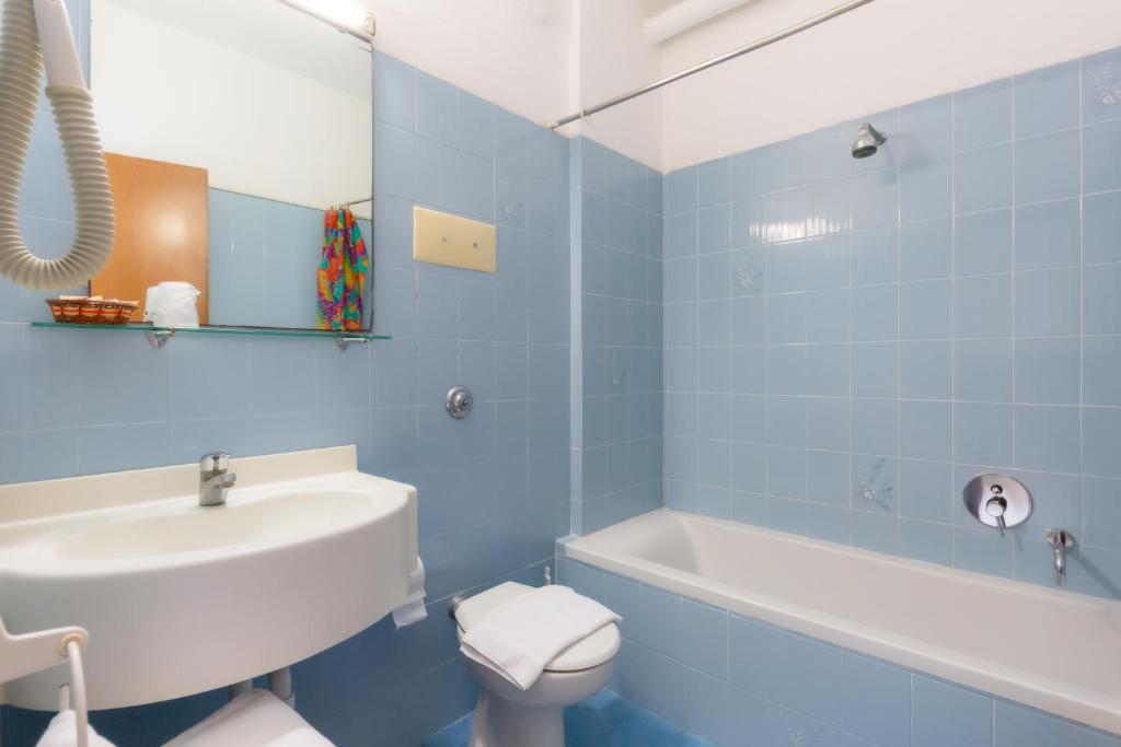 La salle de bains bleue est pourvue d'un lavabo, de toilettes et d'une baignoire. dans l'établissement Hotel Harry's, à Lido di Jesolo