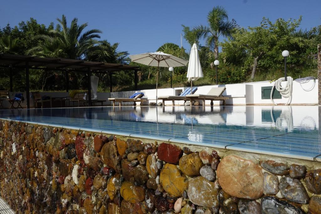 - une piscine avec un mur en pierre à côté d'un complexe dans l'établissement Egesta, villa with private pool, à Calatafimi-Segesta