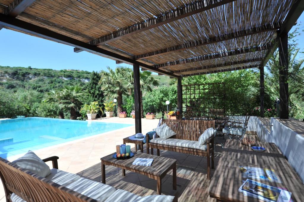 une terrasse avec une pergola en bois à côté d'une piscine dans l'établissement Egesta, villa with private pool, à Calatafimi-Segesta