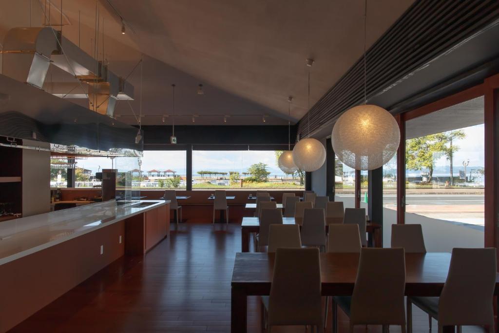 une salle à manger avec tables et chaises et de grandes fenêtres dans l'établissement Iseya, Seaview Private Oceanside Bath, à Unzen