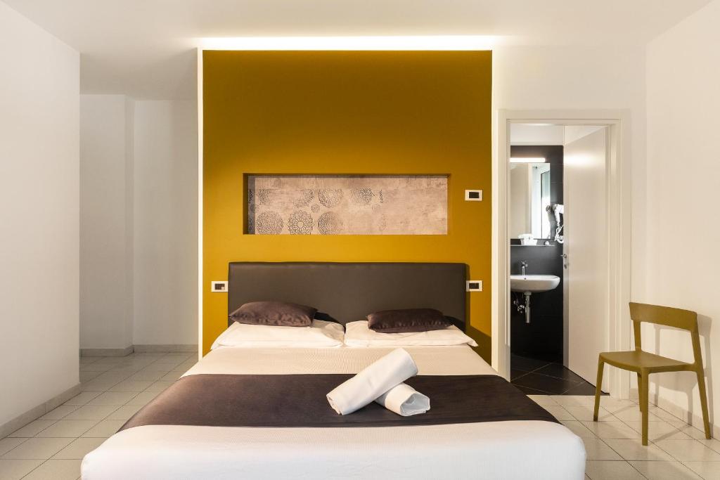 - une chambre avec un grand lit et un mur jaune dans l'établissement Hotel Mediterraneo, à Martinsicuro