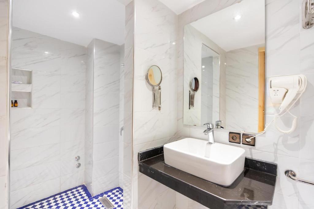 une salle de bain blanche avec un lavabo et une douche dans l'établissement Riad Al Makan Fes & Spa, à Fès 37 autres photos