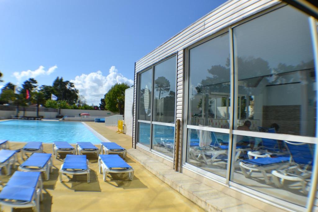 - une piscine avec des chaises longues bleues à côté d'un bâtiment dans l'établissement Le Sherwood - Mobil-Home, à Saint-Jean-de-Monts