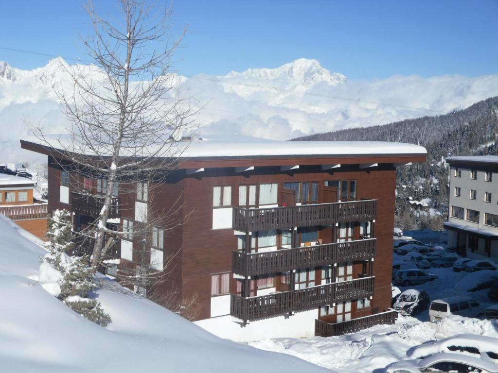 un bâtiment dans la neige avec des montagnes en arrière-plan dans l'établissement CERRO TORRE PLAGNE Du Samedi Au Samedi, à Aime La Plagne