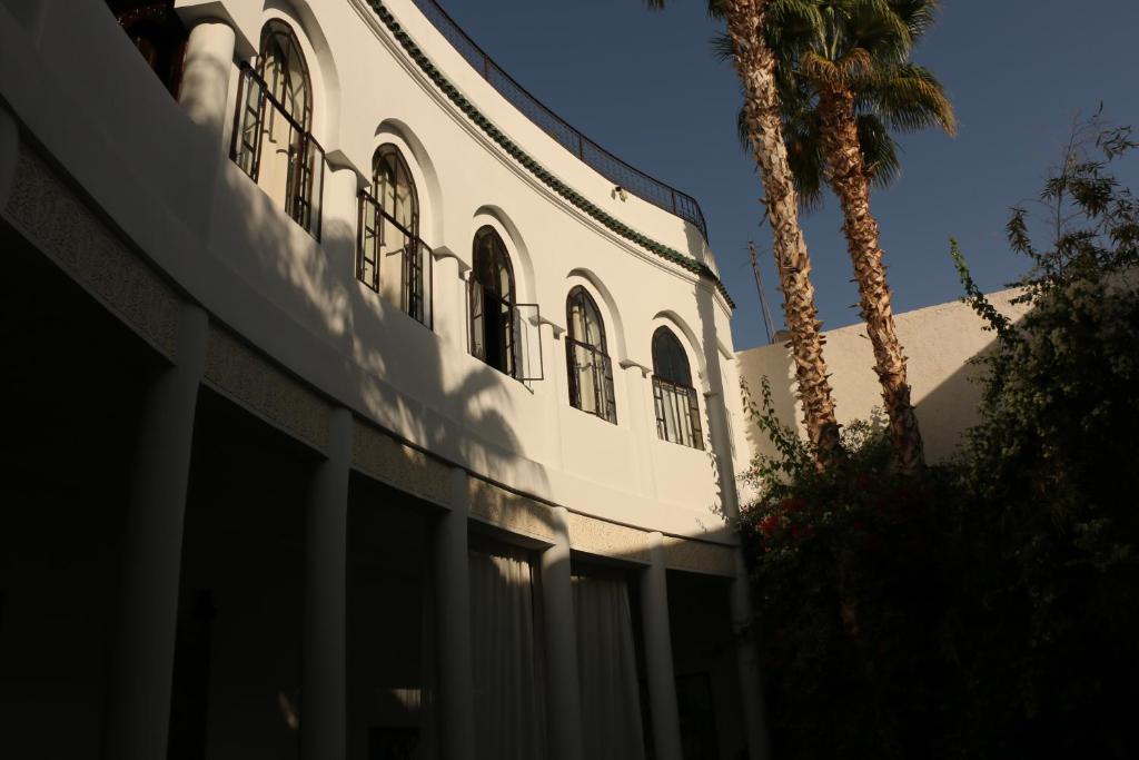 un bâtiment blanc avec un palmier devant dans l'établissement Riad Chergui, à Marrakech