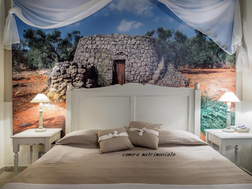 une chambre avec un lit blanc avec un tableau sur le mur dans l'établissement Antica Masseria Rottacapozza, à Torre San Giovanni
