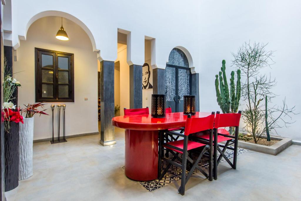 une table et des chaises rouges dans une pièce ornée de plantes dans l'établissement Riad Dar El Masa, à Marrakech