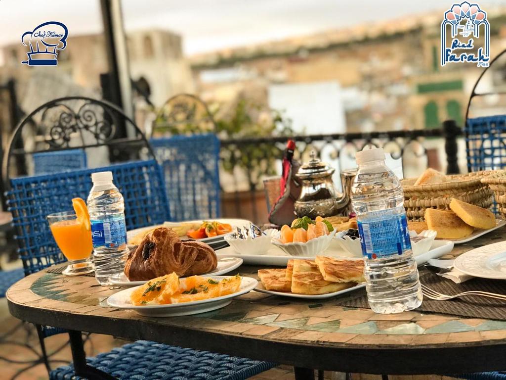 - une table avec des assiettes de nourriture et des bouteilles d'eau dans l'établissement Riad Farah, à Fès