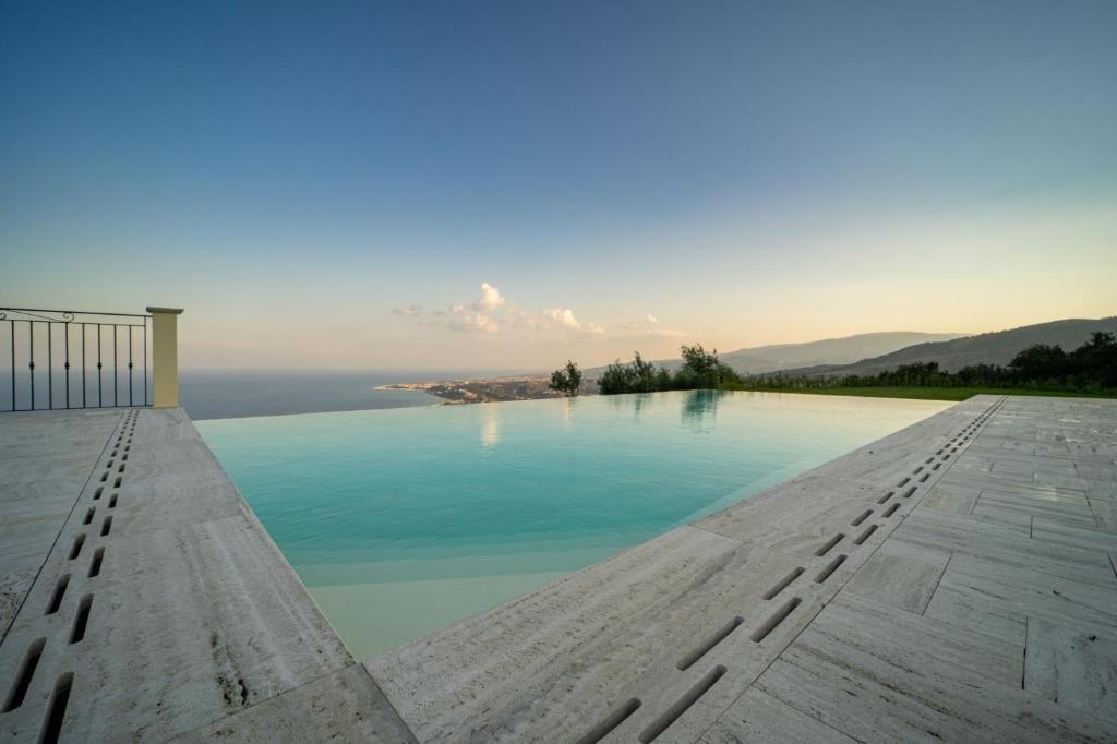 Elle offre une vue sur une piscine d'eau avec des montagnes en arrière-plan. dans l'établissement Villa le Fontanelle, à Gasperina