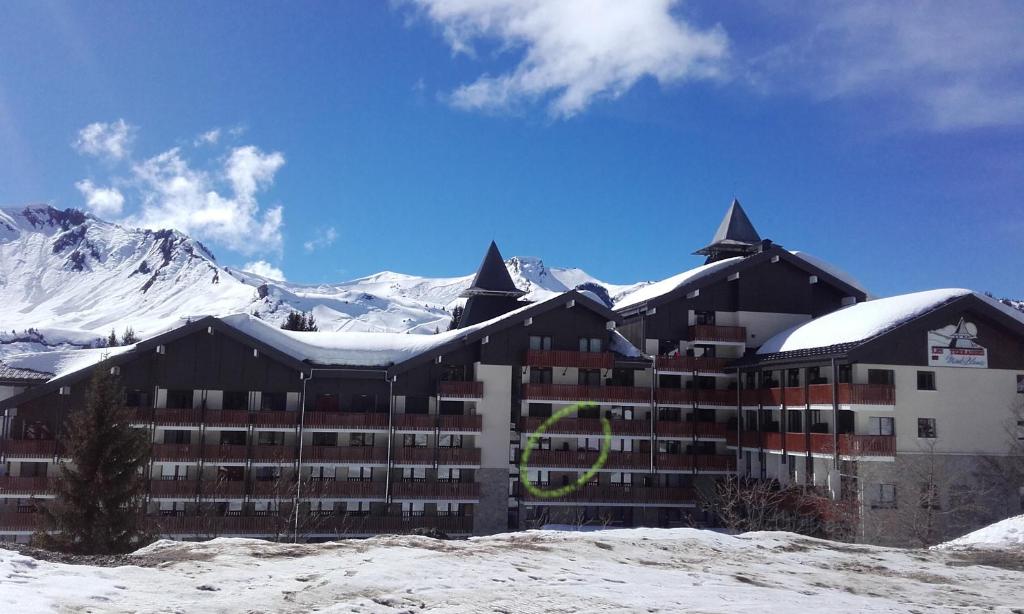 un grand bâtiment avec des montagnes enneigées en arrière-plan dans l'établissement Les Terrasses du Mont blanc, à Praz de Lys - Sommand