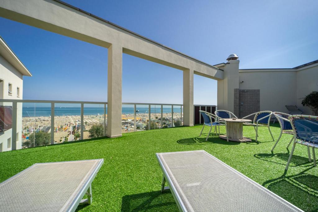 d'un balcon avec des chaises et une table offrant une vue sur l'océan. dans l'établissement Hotel Corallo Rimini, à Rimini