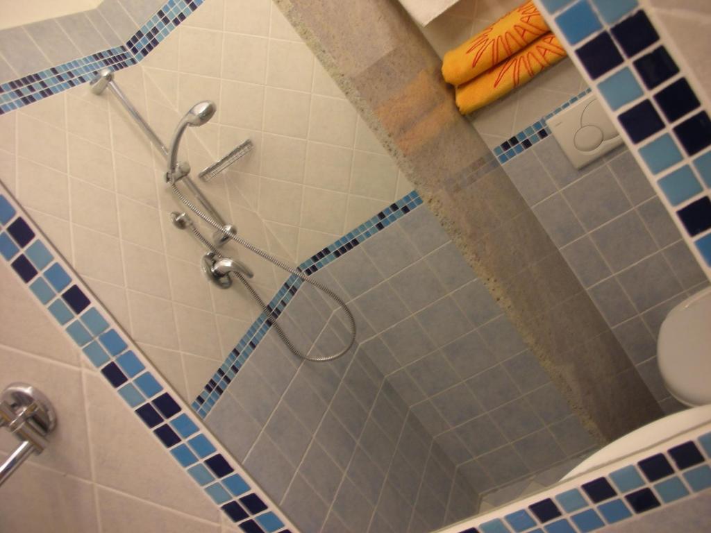 La salle de bains est pourvue d'une douche et de carrelage bleu. dans l'établissement ELISABETTA hotel, à Cesenatico