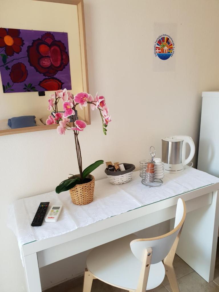 - un bureau blanc avec une fleur dans un vase dans l'établissement Rooms in the Beach, à Catane