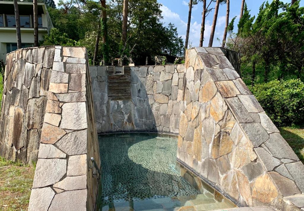 une piscine d'eau dans un mur de pierre avec une porte dans l'établissement Hotel Miki, à Gero