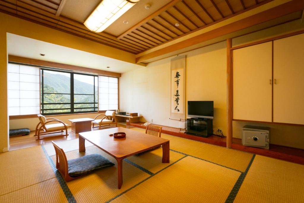 - un salon avec une table, des chaises et une télévision dans l'établissement Hotel Miki, à Gero