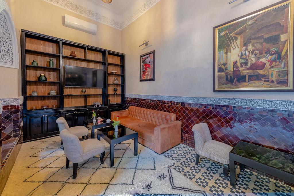 un salon avec un canapé, des chaises et une télévision dans l'établissement Riad Amina, à Marrakech