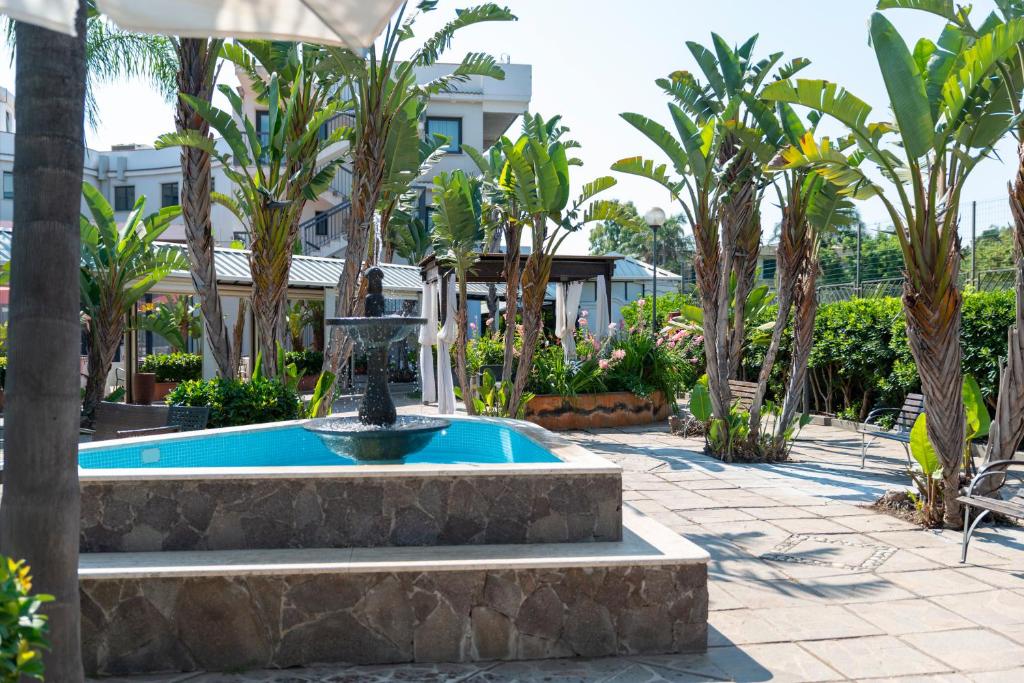 une fontaine au milieu d'une cour avec des palmiers dans l'établissement Atlantis Palace Hotel, à Mascali