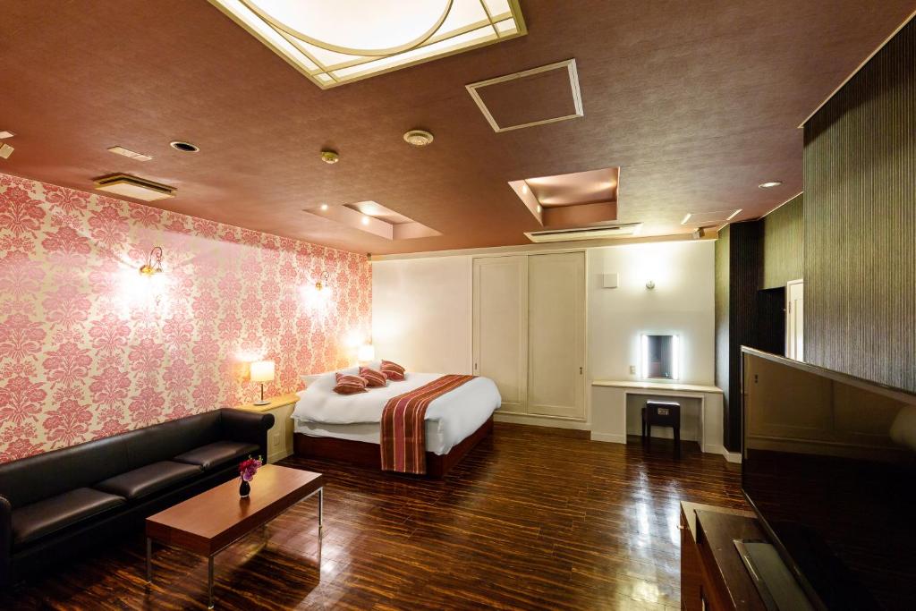 une chambre avec un lit et un canapé dans une pièce dans l'établissement Hotel LOVE JEWEL, à Kitakyūshū