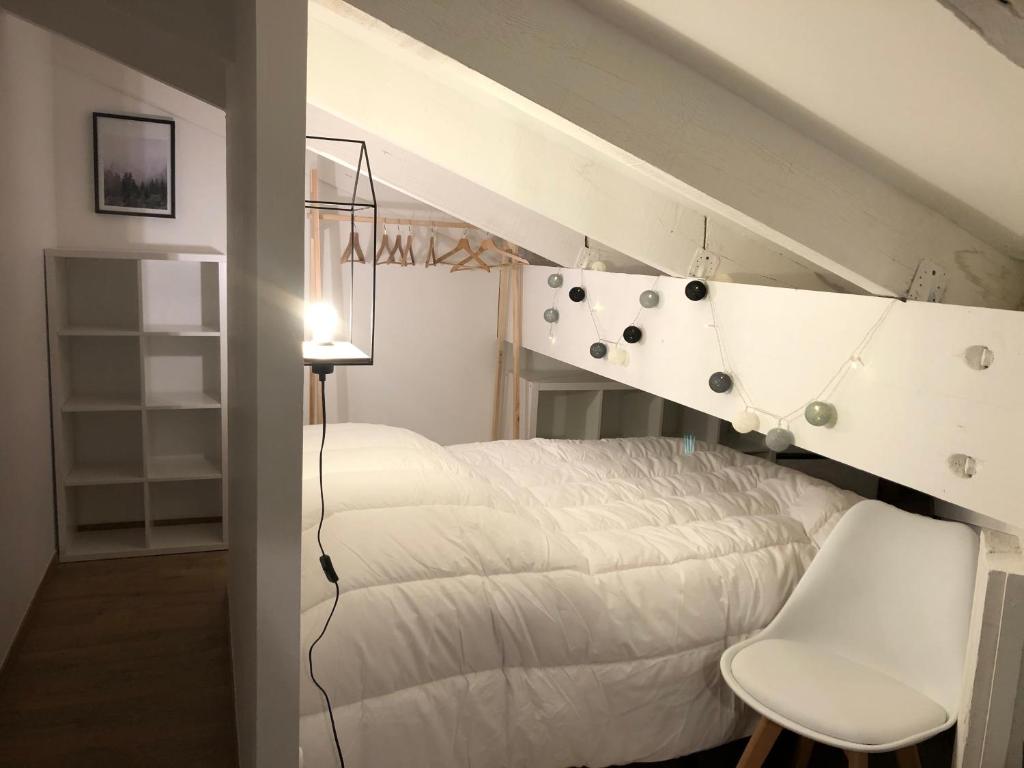 - une chambre avec un lit blanc et une chaise blanche dans l'établissement L'Aire des montagnes, à Bolquère-Pyrénées 2000