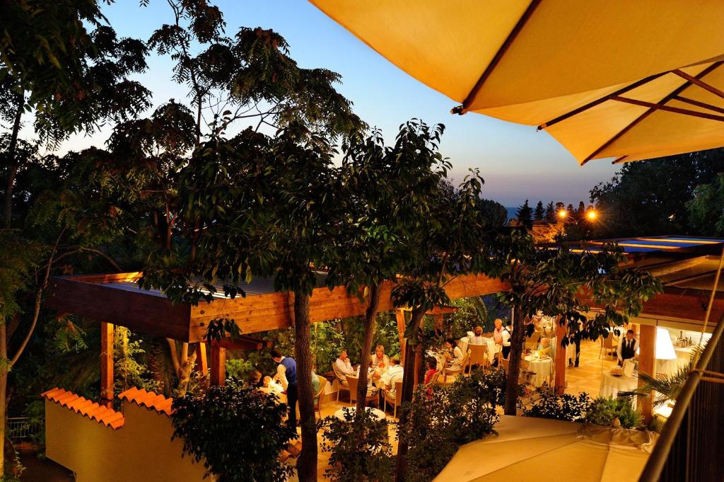 - un restaurant avec des tables et un parasol dans l'établissement Alberi del Paradiso, à Cefalù