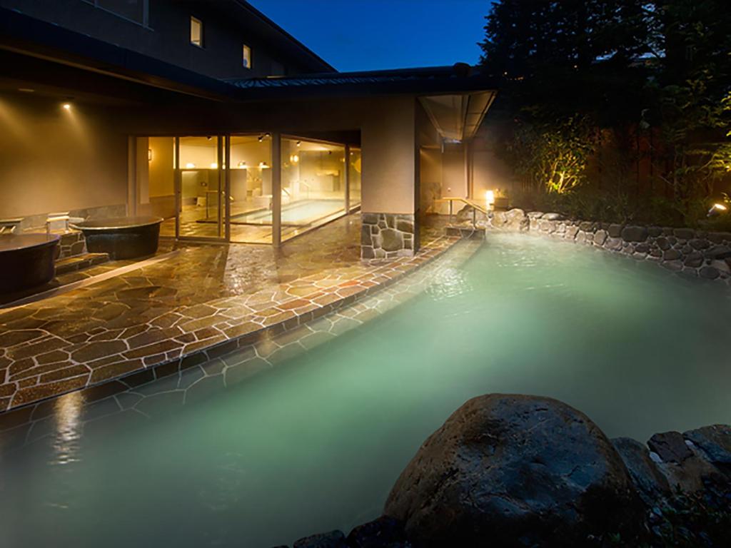 - une piscine d'eau dans un jardin la nuit dans l'établissement Hakone Hisui, à Hakone