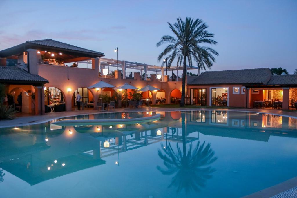 une grande piscine devant une maison dans l'établissement Alma Resort, à Castiadas