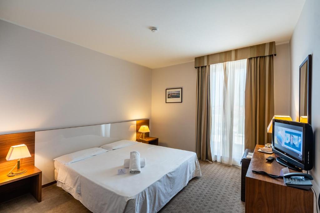 une chambre d'hôtel avec un lit et une télévision dans l'établissement Capo Peloro Hotel, à Torre Faro