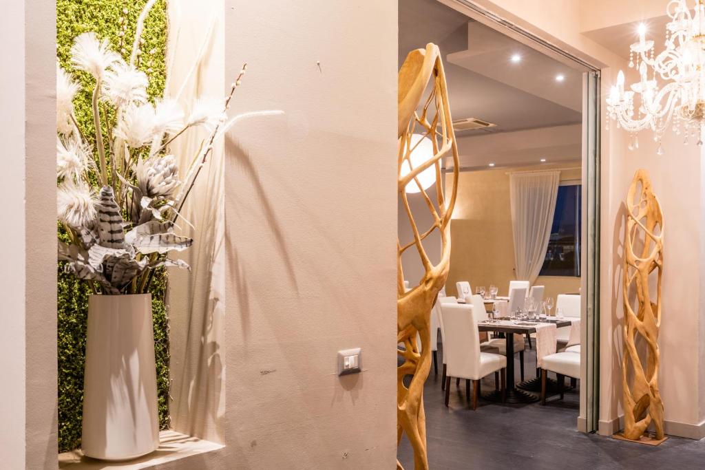 une salle à manger avec une table avec des chaises blanches et des fleurs dans l'établissement Capo Peloro Hotel, à Torre Faro