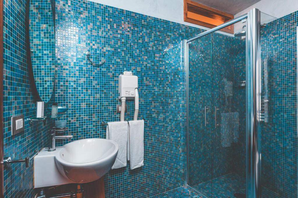 une salle de bain carrelée bleue avec un lavabo et une douche dans l'établissement Lubra Casa Relax, à Massa Lubrense