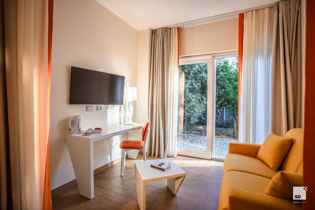une chambre d'hôtel avec un canapé, un bureau et une fenêtre dans l'établissement Tonicello Hotel Resort & SPA, à Capo Vaticano