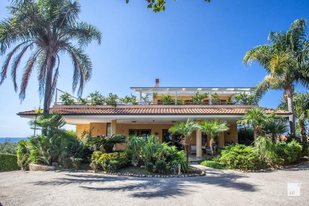 une maison avec des palmiers devant dans l'établissement Tonicello Hotel Resort & SPA, à Capo Vaticano