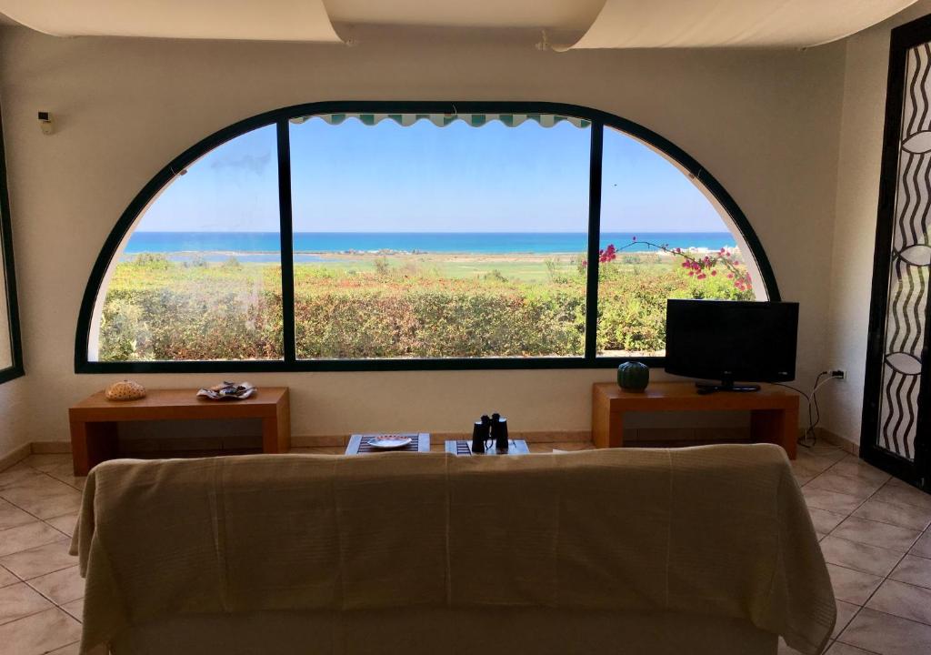 Cette chambre dispose d'une grande fenêtre, d'un canapé et d'une télévision. dans l'établissement Villa panoramica con piscina, à Lido Marini