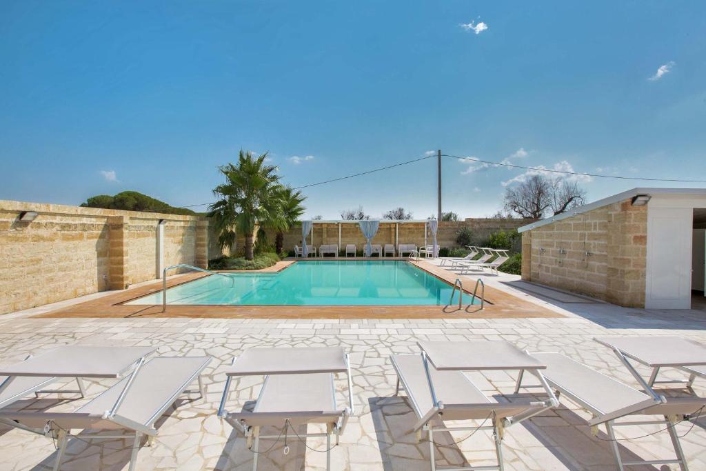 - une piscine avec des chaises blanches dans l'établissement Villa Albarosa by Perle di Puglia, à Ruffano