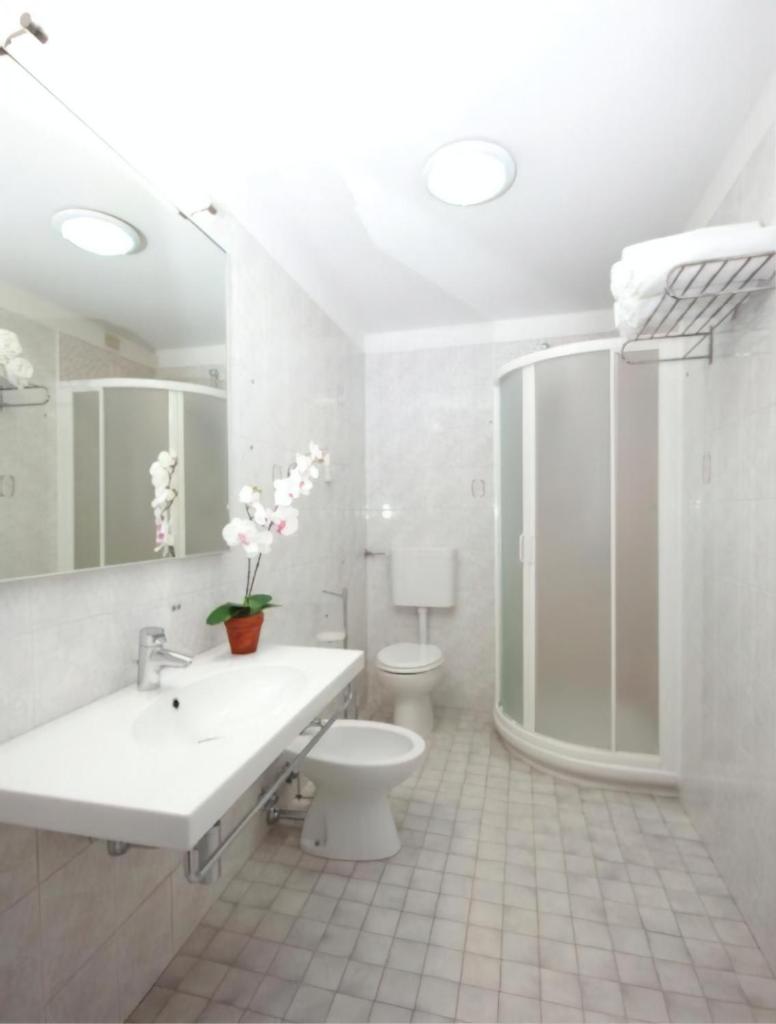 une salle de bain blanche avec toilettes et lavabo dans l'établissement Hotel Storione, à Lido di Jesolo