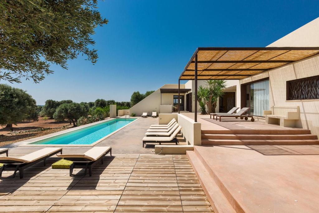 - une piscine avec chaises longues et une maison dans l'établissement Villa Sofia by Perle di Puglia, à Carovigno