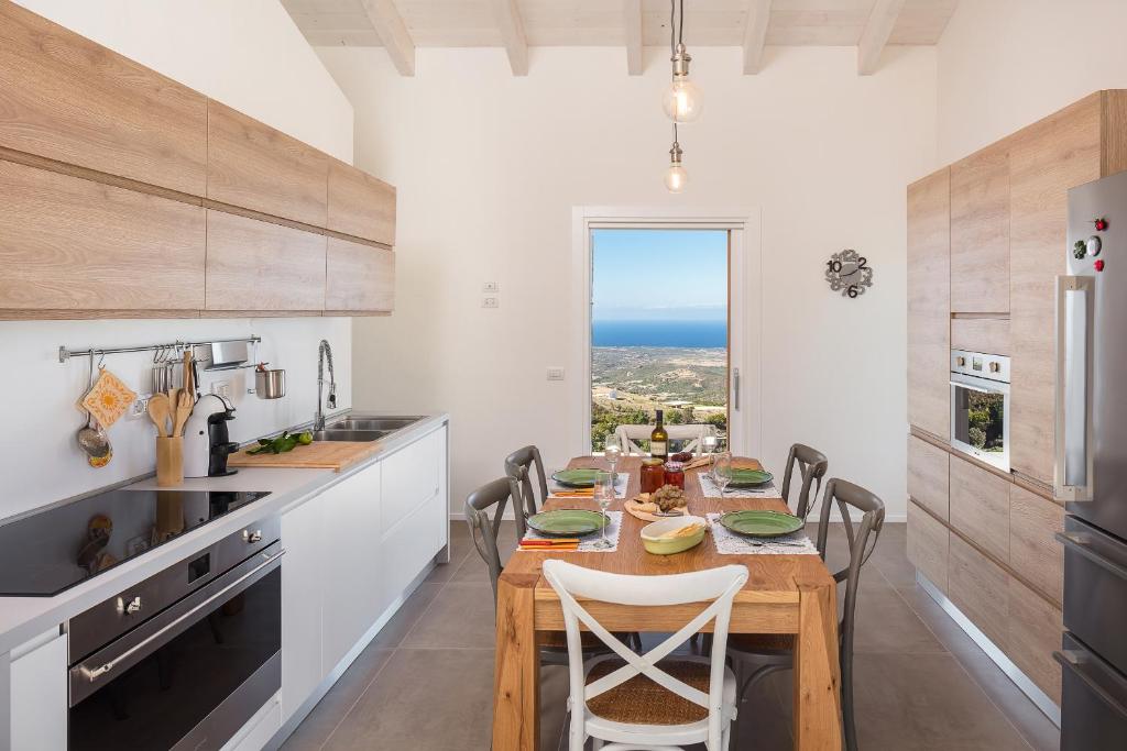 une cuisine avec une table avec des chaises et une salle à manger dans l'établissement Sardegna è - Stazzu di l'Incantu con piscina, à Aglientu