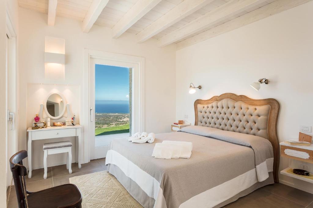 une chambre blanche avec un lit et une grande fenêtre dans l'établissement Sardegna è - Stazzu di l'Incantu con piscina, à Aglientu