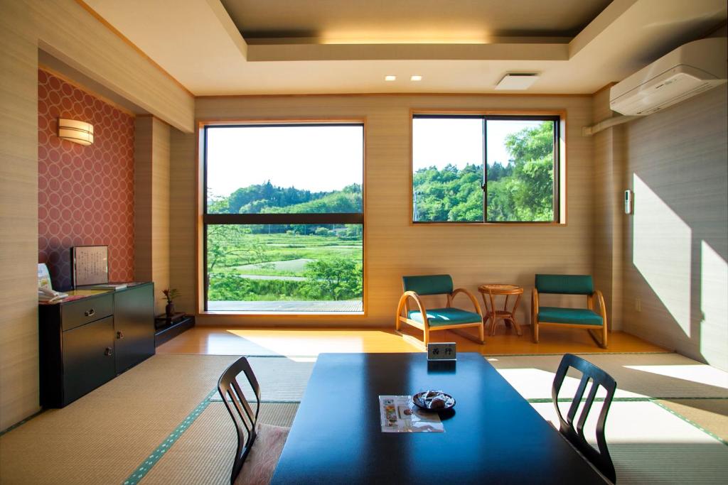une pièce avec une table et des chaises et une grande fenêtre dans l'établissement Shizukatei, à Hiraizumi