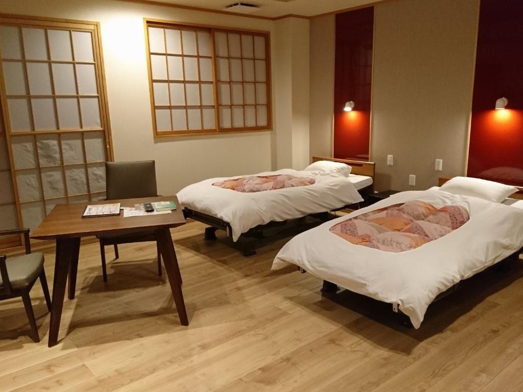 une chambre d'hôtel avec deux lits et une table dans l'établissement Shizukatei, à Hiraizumi
