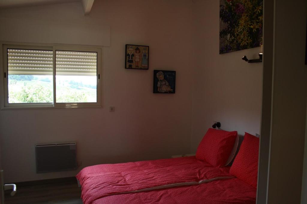 - une chambre avec un lit doté de draps rouges et une fenêtre dans l'établissement la perle du lot gite, à Castelnau-de-Montratier