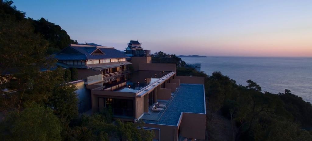 une maison sur une colline à côté de l'océan dans l'établissement THE HIRAMATSU HOTELS & RESORTS ATAMI, à Atami