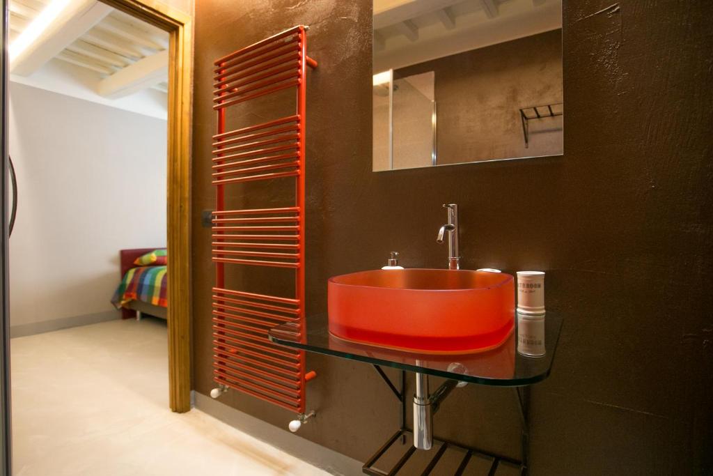 La salle de bains est pourvue d'un lavabo rouge et d'un miroir. dans l'établissement BellaVista di Mammi, à Castiglion Fiorentino