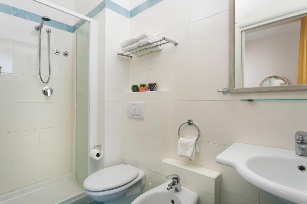 une salle de bain blanche avec toilettes et lavabo dans l'établissement Ambasciatori Hotel - Beach Front -Breakfast XXL & Brunch until 12 30pm, à Misano Adriatico