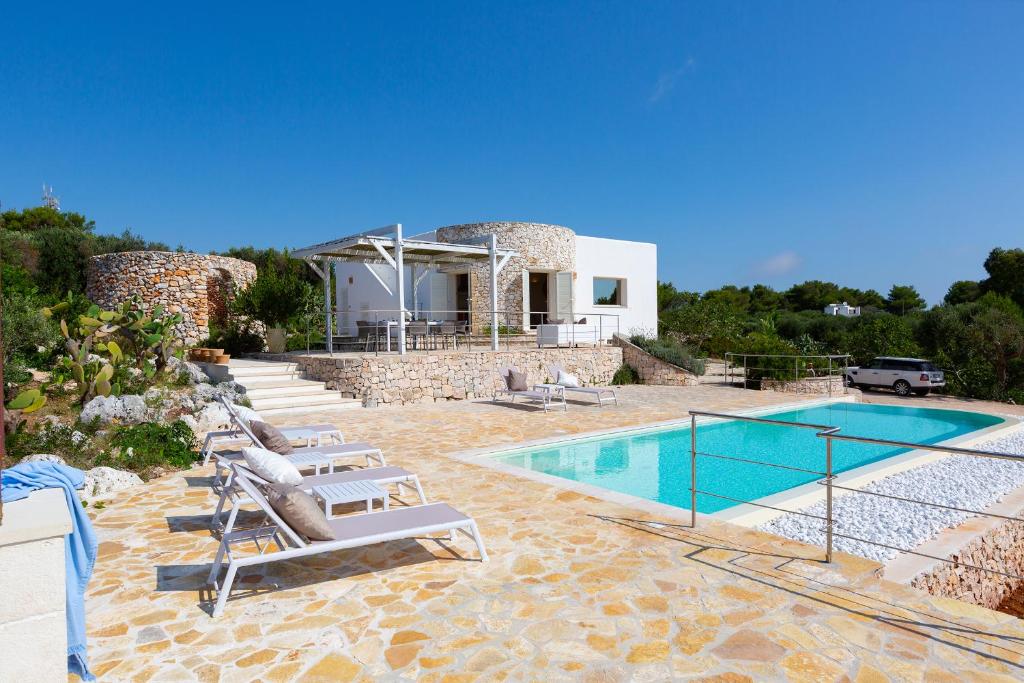 une villa avec piscine et chaises longues dans l'établissement VILLA BIANCA con piscina e vista mare, à Gagliano del Capo
