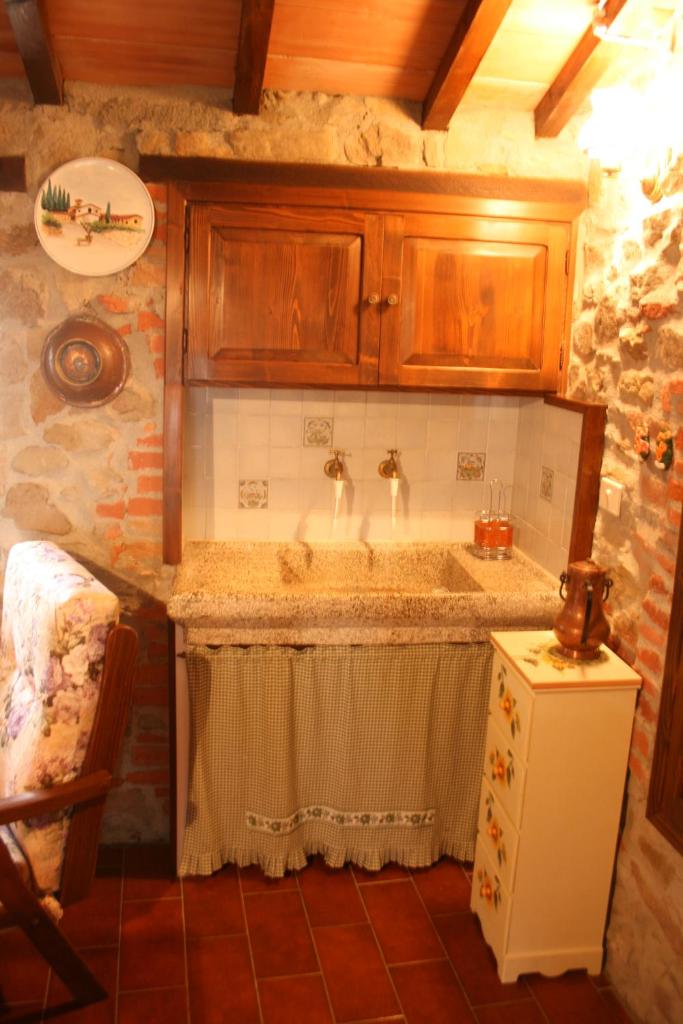 une cuisine avec un évier et des armoires en bois dans l'établissement PODERE CAPANNE, à Sinalunga