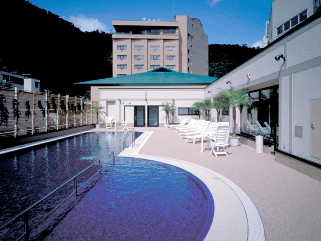 une piscine avec des chaises et un bâtiment dans l'établissement Hanamomiji, à Jozankei